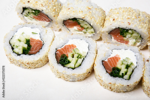 Sushi on a white background in sesame. Philadelphia with cucumber roll. Food.