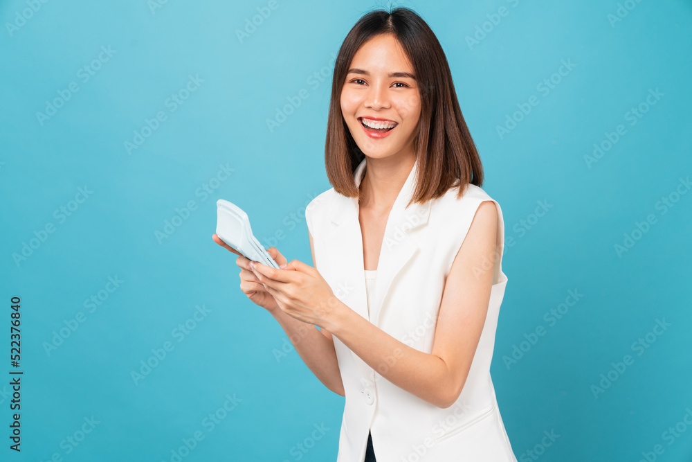 Cheerful beautiful Asian woman stand with hand holding white calculator on blue background. Cheerful beautiful Asian woman stand with hand holding white calculator on blue background.