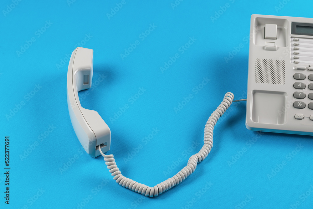 Wired retro phone with keys and a removed handset on a blue background.