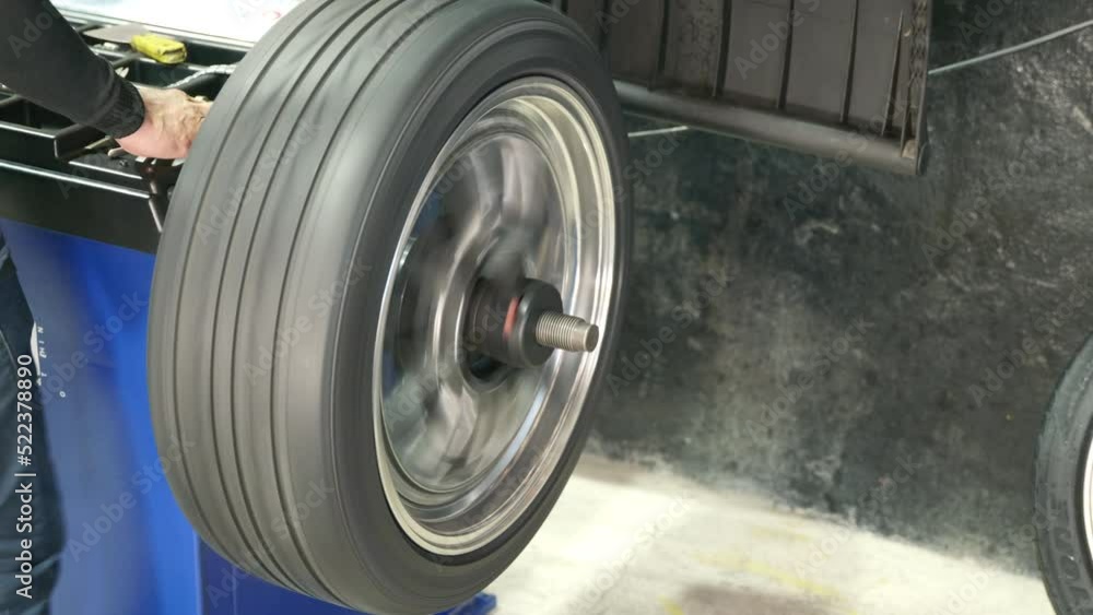 Auto mechanic balancing wheel places weights on steel rim with machine ...