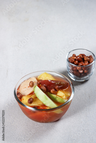 Asinan Buah Bogor or Rujak Buah, fruit pickle made from sliced fresh tropical fruits on sweet, sour and spicy red soup. Topped with fried peanuts.