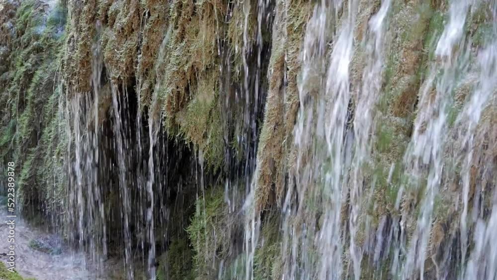 Closeup water stream on moss and lichen on rock vertical wall. Water pours from moss and drop on the air to the ground. Similar to cave scenery. Closeup water stream on moss and lichen on rock vertical wall. Water pours from moss and drop on the air to the ground. Similar to cave scenery.