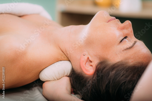 Kizhi or herbal bolus bags Ayurveda massage in a beauty salon, therapist pressing herbal bolus bags onto client’s neck.