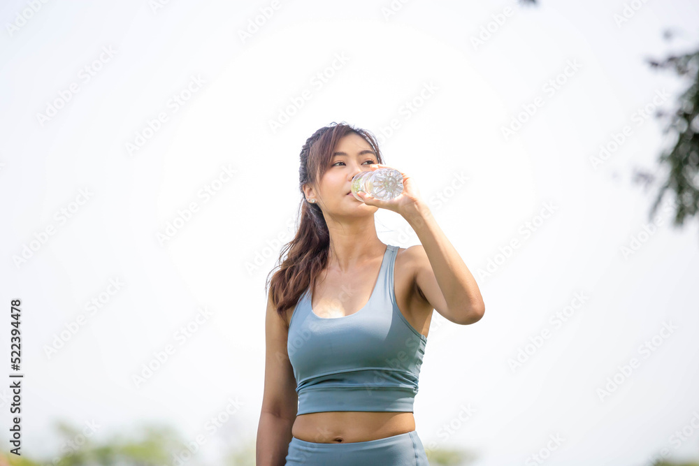 Athlete young beautiful woman drinking water from a plastic bottle at summer green park, Sport woman drinking water after work out exercising Athlete young beautiful woman drinking water from a plastic bottle at summer green park, Sport woman drinking water after work out exercising