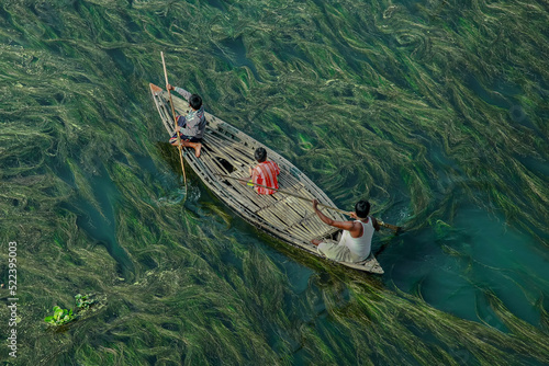 Fishermen are seen floating on top of algae as they search for potential catch in the sharp green waters of a river. The Sirajganj spot in Bangladesh is a popular place. photo