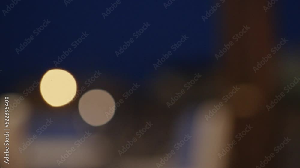 Male hand picks up glass of cold beer on background of blurry lights, close up Male hand picks up glass of cold beer on background of blurry lights, close up