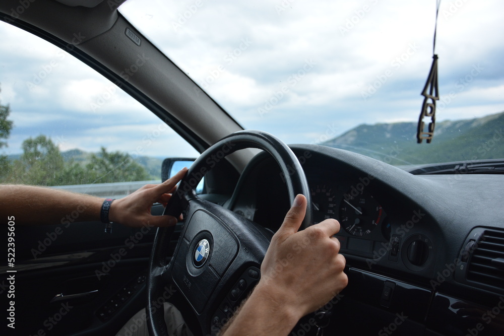 Zwei Hände eines Mannes lenken das Lenkrad eines BMW 5er e39, Blick vom  Beifahrer-Sitz, Virpazar, Montenegro, 12.07.2019 Stock Photo