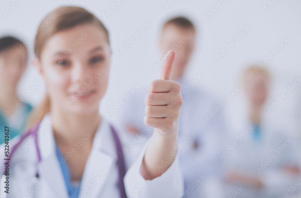 Attractive female doctor in front of medical group showing ok Attractive female doctor in front of medical group showing ok