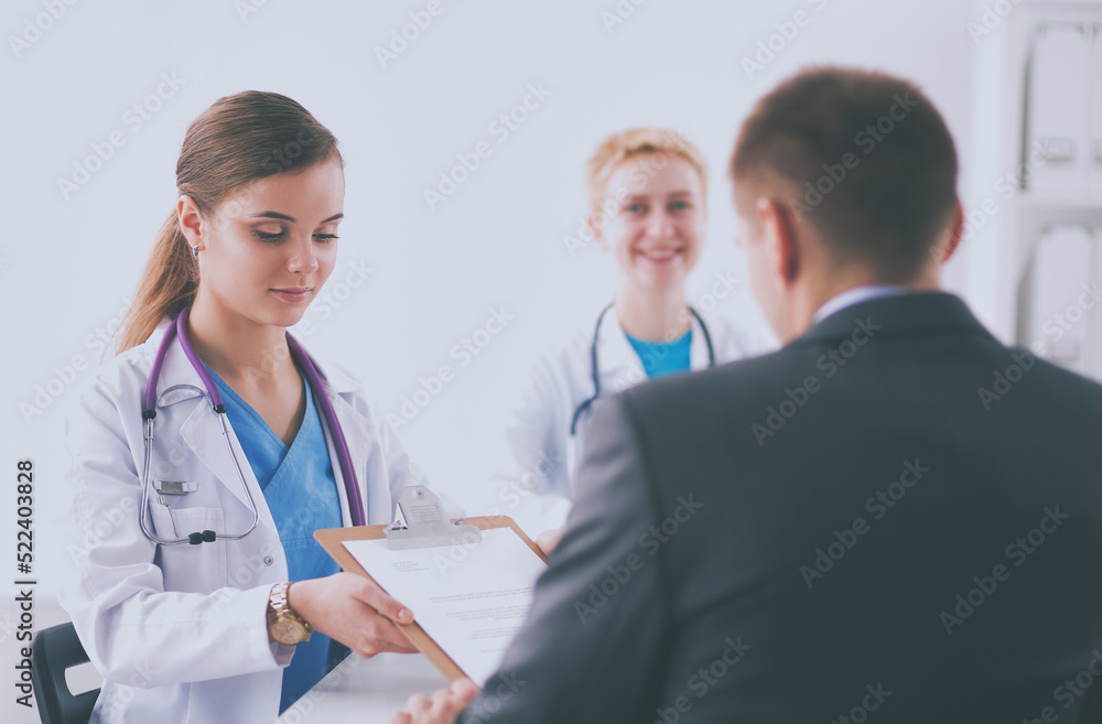 Beautiful young smiling female doctor sitting at the desk Beautiful young smiling female doctor sitting at the desk