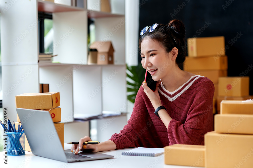 Online business owner Asian woman answering the phone talking to a customer and take note of the details of the delivery customer Negotiated address to verify correct details. Online business owner Asian woman answering the phone talking to a customer and take note of the details of the delivery customer Negotiated address to verify correct details.
