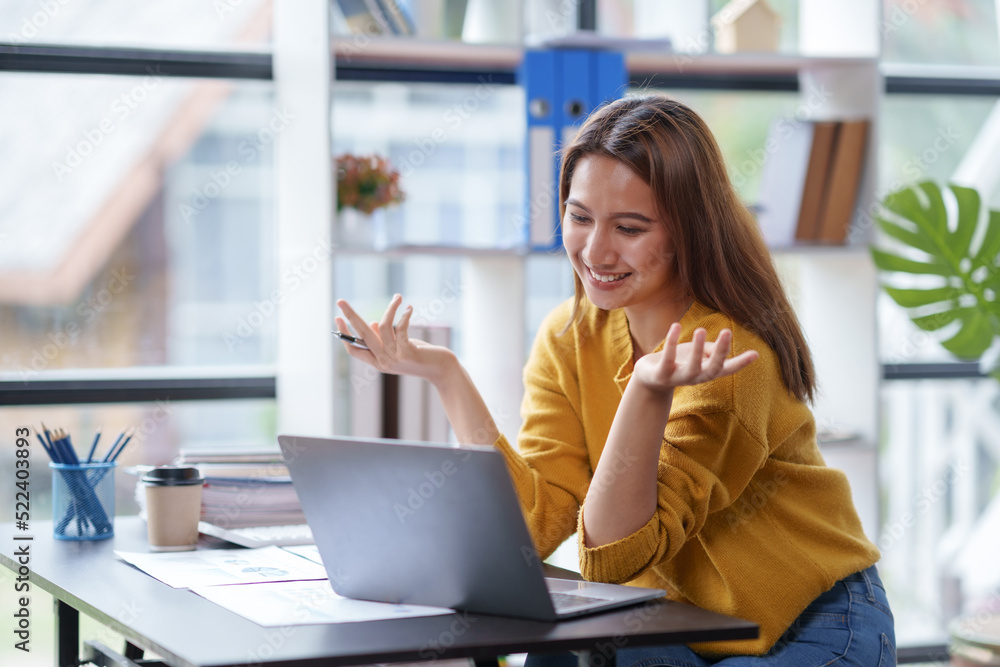 Beautiful Asian businesswoman is on video call with customer on laptop in office and has a negotiating gesture. smiling and happy face. Beautiful Asian businesswoman is on video call with customer on laptop in office and has a negotiating gesture. smiling and happy face.