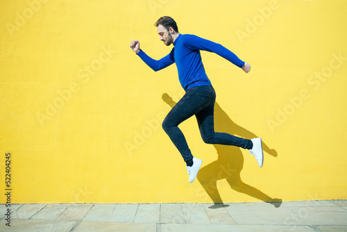 young man jumping for success on a yellow background