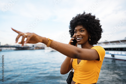 Happy young african american young woman talking with cellphone in city