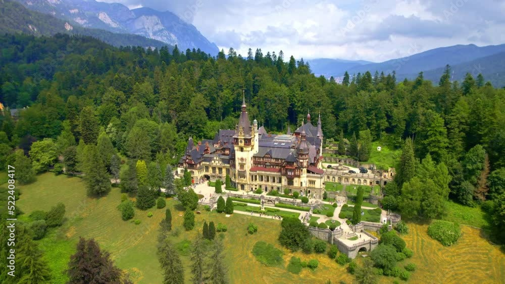 Aerial drone view of The Peles Castle in Romania. Castle with gardens and tourists in Carpathians, lush forest around it Aerial drone view of The Peles Castle in Romania. Castle with gardens and tourists in Carpathians, lush forest around it