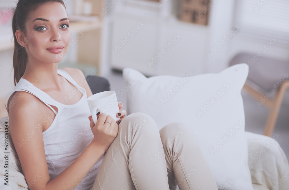 Portrait of young beautiful woman with a cup on sofa at home Portrait of young beautiful woman with a cup on sofa at home