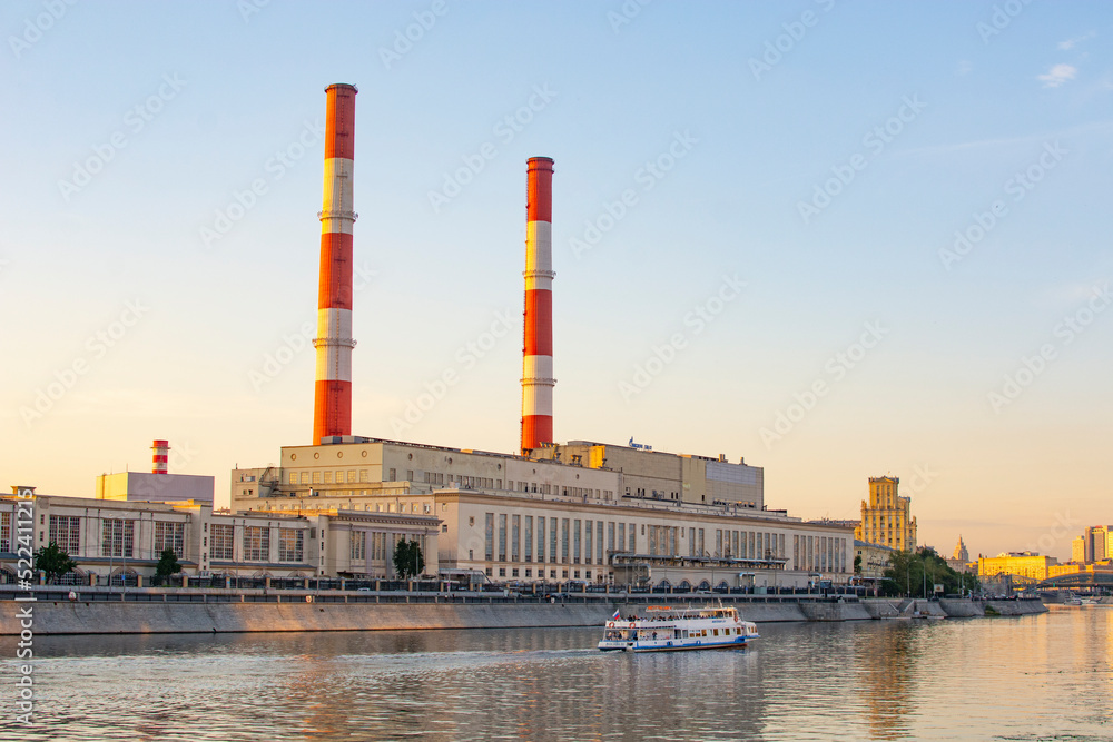 Moscow, Russia - August 2, 2022 : thermal power plant in Moscow on the waterfront and a motor ship taking a boat trip Moscow, Russia - August 2, 2022 : thermal power plant in Moscow on the waterfront and a motor ship taking a boat trip