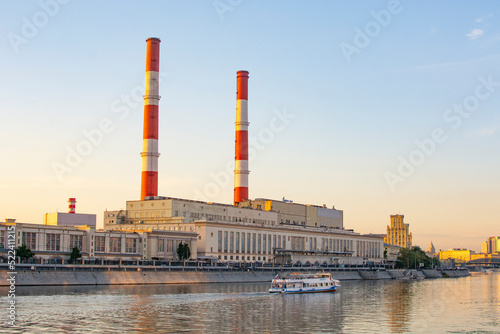 Moscow, Russia - August 2, 2022 : thermal power plant in Moscow on the waterfront and a motor ship taking a boat trip