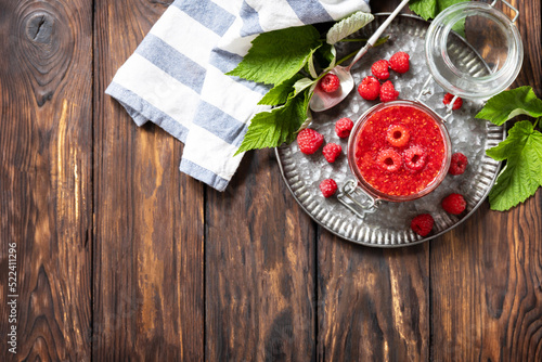 Homemade preservation. Delicious raspberries jam or jelly on a rustic wooden table. View from above. Copy space.