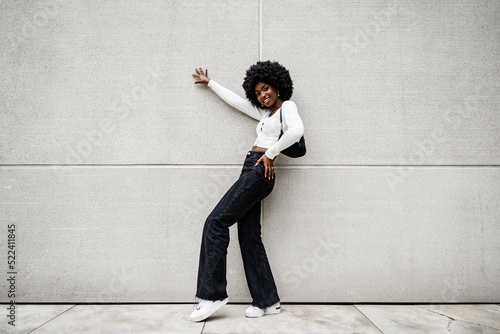 Slika na platnu Black woman with afro hair posing in front of a gray concrete wall