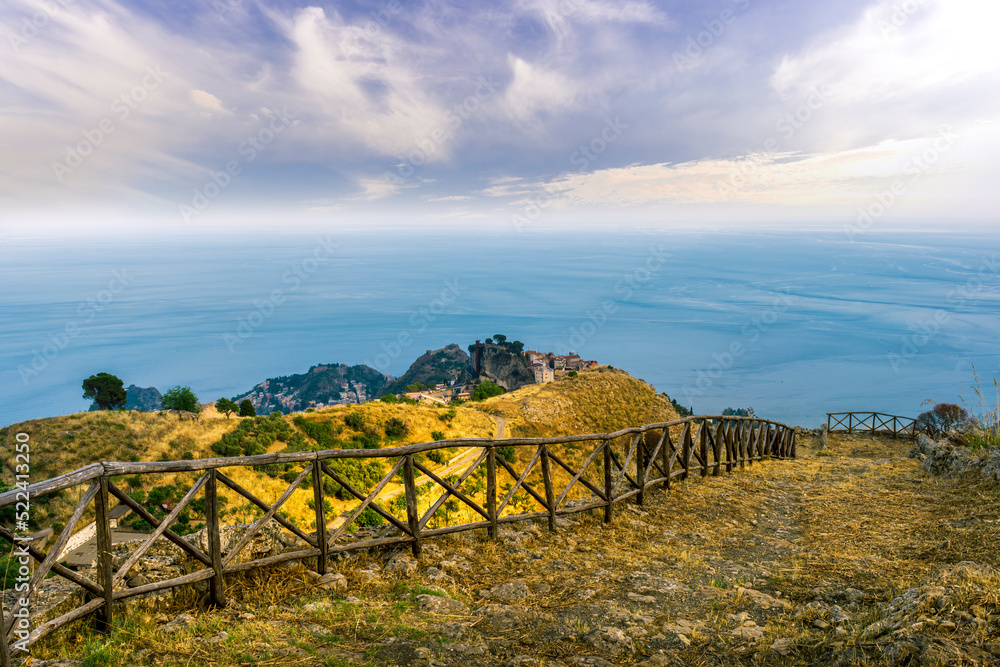 Obraz premium mountain landscape with a hiking trail leading to a mountain town and beautiful blue seashore far away