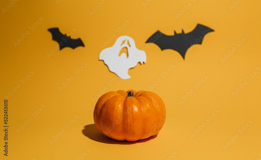 Fototapeta premium Fresh ripe pumpkin on orange background. Space with bats and ghost Halloween concept