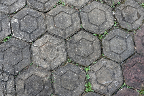 Old Hexagonal shaped paving blocks concrete with some wild grass. used in the home page, office and others.