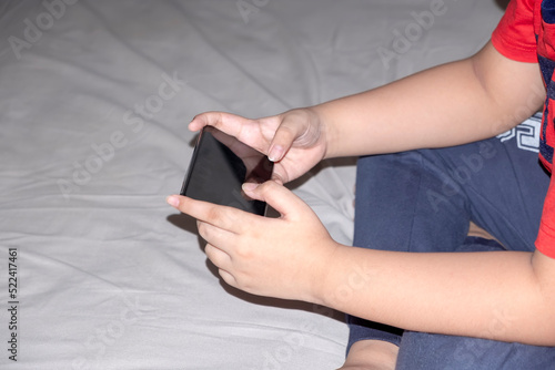 Photo of a boy hands playing a game on a mobile cell phone from behind. gamer boy playing video games holding Smartphone working mobile devices. cell telephone technology 