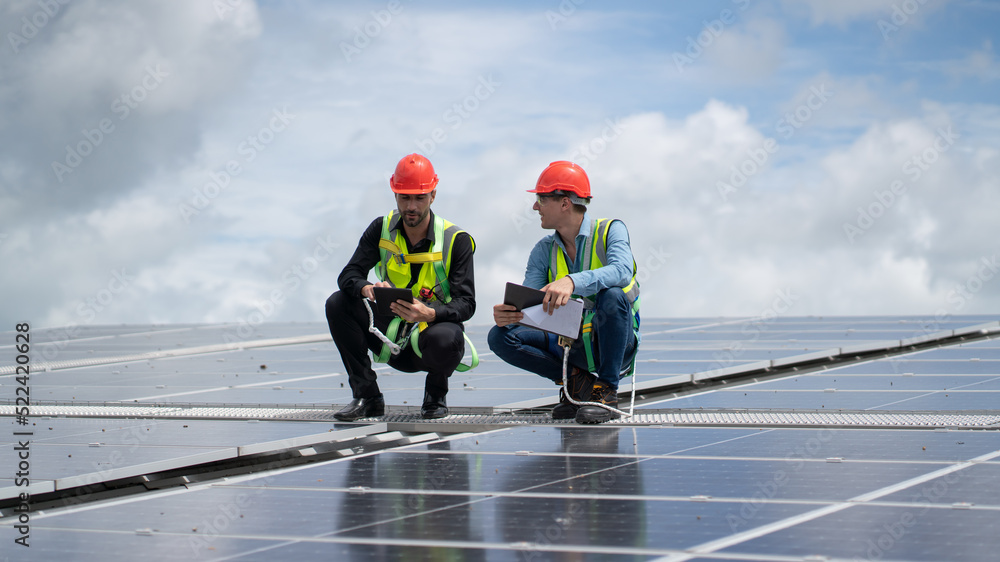 Fototapeta premium Construction workers clean solar panels for energy.Renewable Energy Battery Clean Mountain Climber Activities Work Uniforms.Managers discuss electric power ecology, human, renewable energy. 