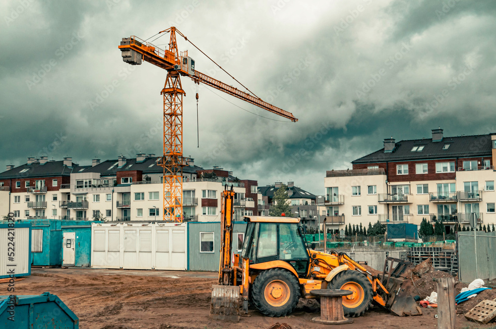 Construction site with a yellow tower crane and yellow digger Construction site with a yellow tower crane and yellow digger
