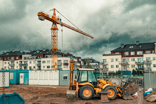 Construction site with a yellow tower crane and yellow digger