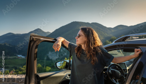 Young beautiful woman traveling by car in the mountains, summer vacation and adventure photo
