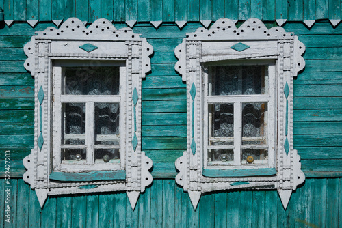 Facade of a traditional rural wooden house with ornamental painted frames with fancy carvings.