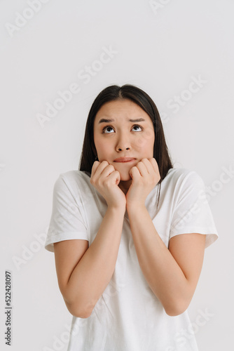 Asian scared woman wearing t-shirt posing and looking upward
