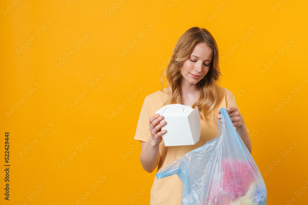 Young blonde woman wearing t-shirt posing with trash bag Young blonde woman wearing t-shirt posing with trash bag