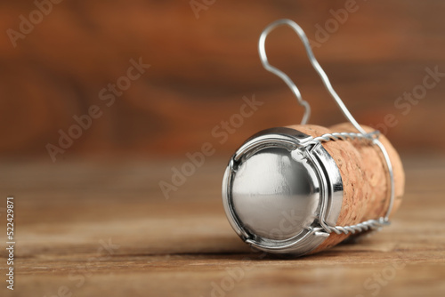 Sparkling wine cork with muselet cap on wooden table, closeup. Space for text