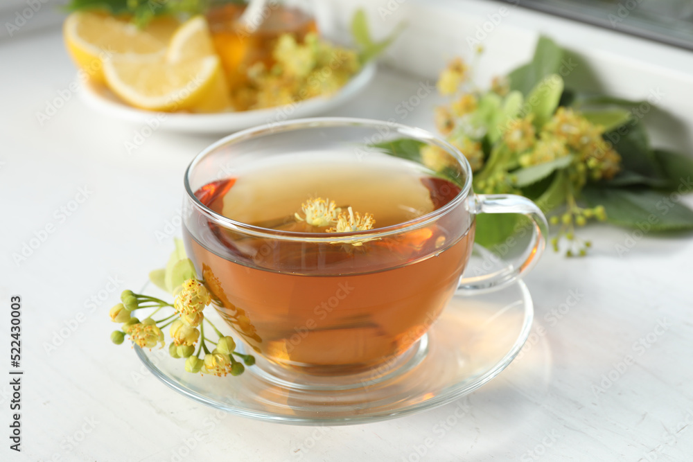 Cup of tea with linden blossom on white windowsill Cup of tea with linden blossom on white windowsill