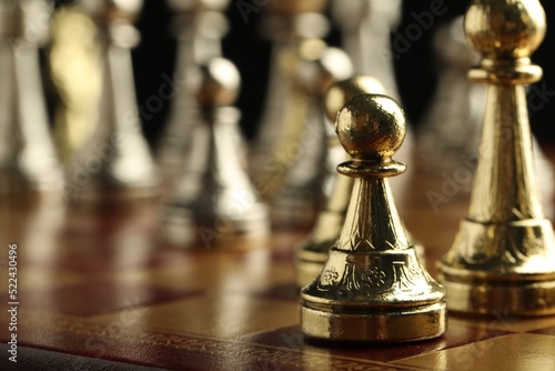 Chessboard with game pieces on black background, closeup. Space for text