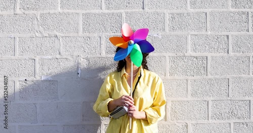 Woman hiding face behind colorful pinwheel photo