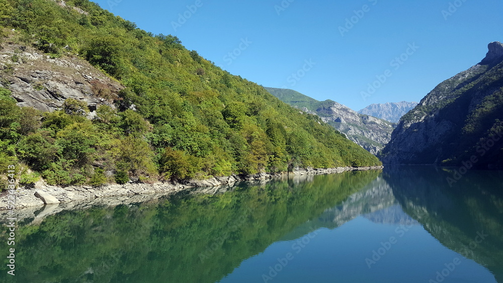 Albania, Lake Koman is a reservoir on the Drin River in northern Albania, surrounded by dense forested hills, vertical slopes, deep gorges and a narrow valley