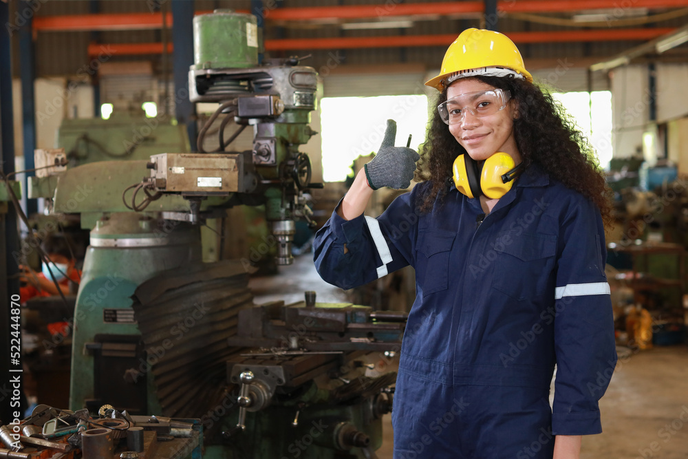 Technician engineer or worker woman in protective suit smiling and showing thumb up maintenance operation or checking lathe metal machine at heavy industry manufacturing factory. Metalworking concept Technician engineer or worker woman in protective suit smiling and showing thumb up maintenance operation or checking lathe metal machine at heavy industry manufacturing factory. Metalworking concept