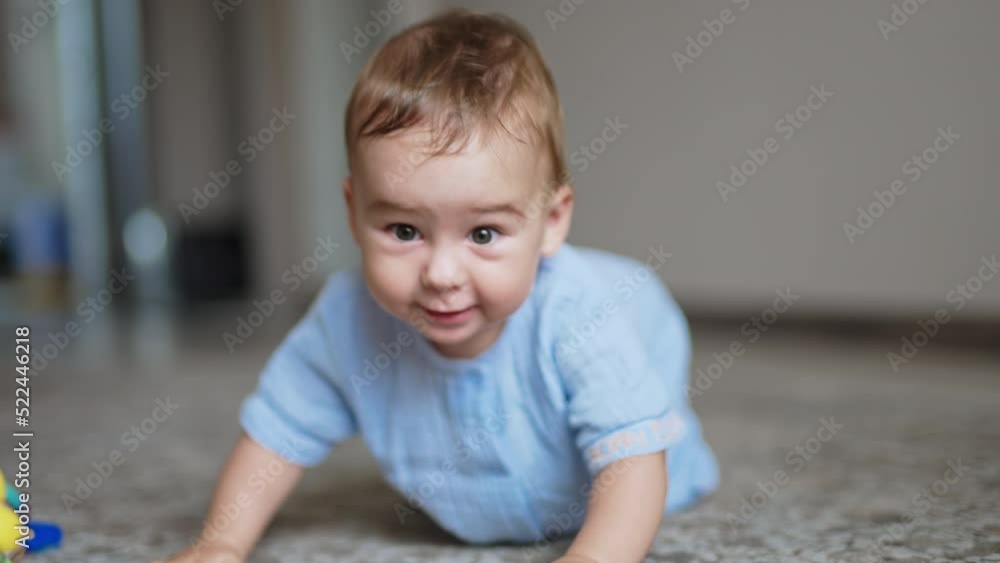 Adorable cheerful laughing toddler standing on all fours on the floor and swaying. Little kid playing with a toy. Adorable cheerful laughing toddler standing on all fours on the floor and swaying. Little kid playing with a toy.