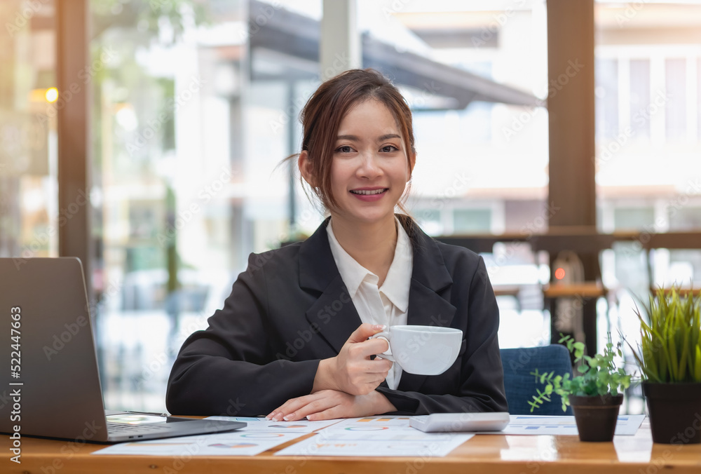 marketing, finance, accounting, planning, businesswoman holding a cup of coffee online meeting Profit Analysis with Graph Statistics Use a laptop and a calculator to calculate your company balance. marketing, finance, accounting, planning, businesswoman holding a cup of coffee online meeting Profit Analysis with Graph Statistics Use a laptop and a calculator to calculate your company balance.