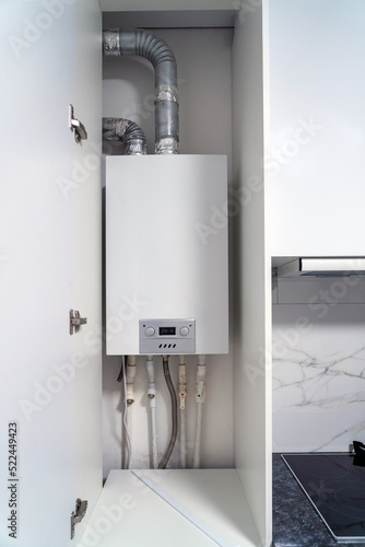 фотографія Opened kitchen cabinet and LPG gas boiler inside furniture