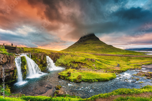 Landscape of sunset over Kirkjufell mountain with Kirkjufellsfoss waterfall and colorful pileus cloud on summer at Iceland