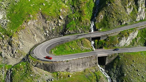 Aerial drone view of nature in Romania. Transfagarasan route in Carpathian mountains with moving cars, rocky slopes with greenery