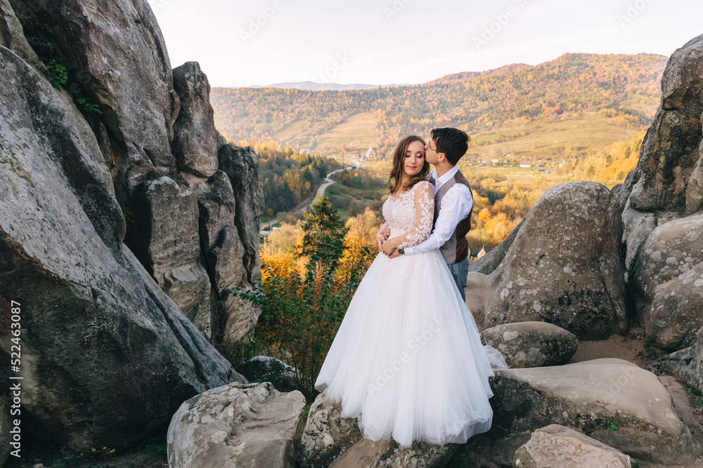 Young beautiful couple of man and woman in a white wedding dress and suit walking on the stone mountains. Wedding day in nature.