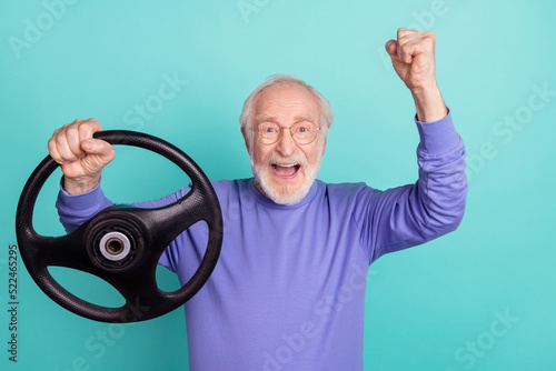 Portrait of delighted overjoyed person hold wheel raise fist celebrate isolated on aquamarine color background