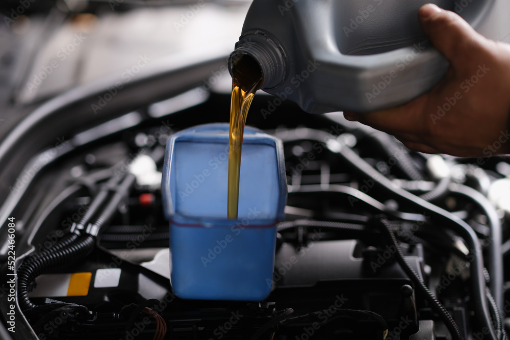 Fototapeta premium Pour gear oil into car through watering can
