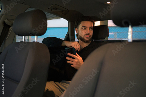 Business Latin man inside of a car with a mobile phone