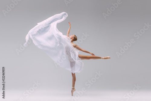 Fotografia Portrait of young ballerina dancing with fabric isolated over grey studio background